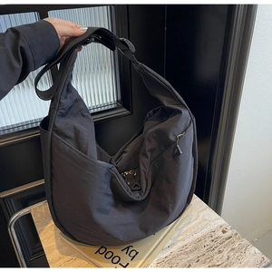 Detail of adjustable shoulder strap and plastic buckle on nylon crossbody crescent bag