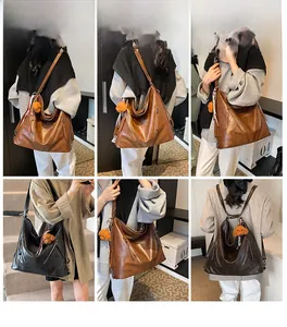 Modella che mostra la borsa tote versatile grande in nero e marrone con ciondolo orso