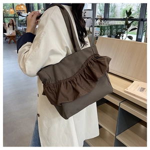 Close-up of deep brown canvas tote bag featuring stylish ruffled pleats and wide straps