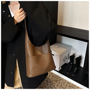 Detailed view of brown faux leather hobo bag with front pockets and wide shoulder strap