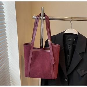Detail of burgundy suede tote bag featuring adjustable leather strap and gold metal buckle