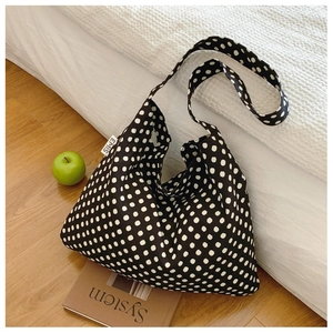 Close-up of black and white polka dot canvas hobo bag with a side brand logo label