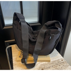 Detail of black nylon crescent bag with wide adjustable strap and metal zipper