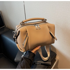 Detail of khaki leather pillow bag with lychee texture and wide fabric strap