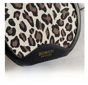 Close-up of leopard print canvas and black leather detail with gold BOWEN logo engraving