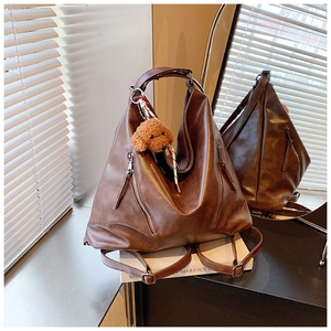 Dettaglio della borsa tote in pelle PU marrone con cerniere e ciondolo di peluche