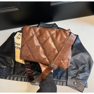 Macro shot of dark brown quilted shoulder bag with soft faux leather texture and strap