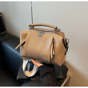 Detail of tan pebble leather bag with double zippers and wide logo fabric strap