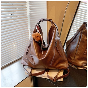 Dettaglio della borsa in pelle marrone con doppie cerniere e ciondolo a forma di orsetto