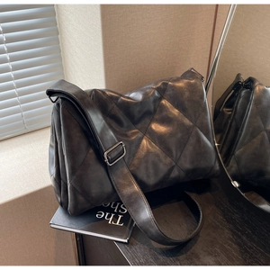 Detail of black quilted shoulder bag with soft faux leather and silver metal buckles
