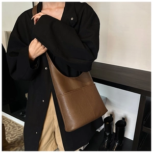 Detail view of large brown faux leather tote bag with wide strap on shoulder