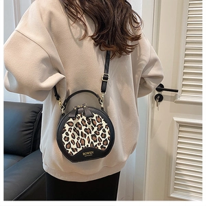 Detail of round leopard print bag with golden hardware and brand logo on the bottom