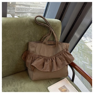 Close-up of a brown tote bag with ruffled pleats on a vintage corduroy chair