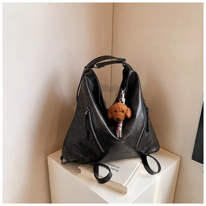 Dettaglio di borsa tote nera versatile con struttura a triangolo e ciondolo orsetto di peluche