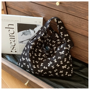 Detail of black canvas tote bag with white bow pattern placed in a wooden drawer