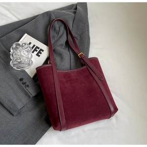 Chic burgundy faux suede tote bag with leather straps on a grey suit jacket