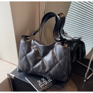 Detailed view of black quilted crossbody bag with high texture leather and wide shoulder strap