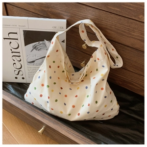 Detailed close-up of a white tote bag with colorful polka dots in a cozy wooden drawer