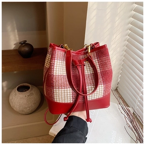 Détail du sac seau à motif pied-de-poule rouge avec cordon en cuir et dorures
