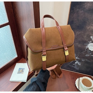 Detail der matten braunen Wildledertasche mit goldenen Schnallen und verstärktem Griff