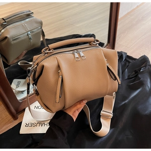 Detailed macro view of camel lychee grain leather handbag with wide woven strap