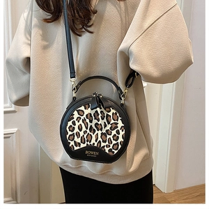 Close-up of leopard print round crossbody bag featuring golden hardware and logo detail