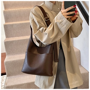 Detailed macro view of retro brown faux leather tote bag with wide shoulder strap