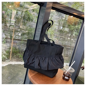 Macro detail of the ruffled design and durable fabric on this black tote bag