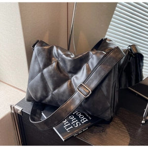 Detail of black quilted leather crossbody bag with adjustable wide strap and silver buckle