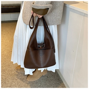 Detail view of large dark brown leather tote bag showing side pocket and metal clasp closure