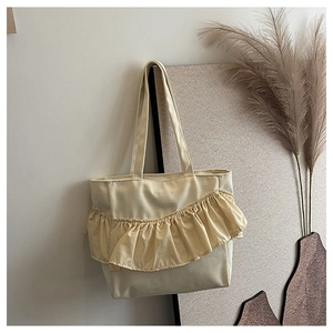 Detail of cream canvas tote bag featuring unique pleated ruffle trim and wide strap