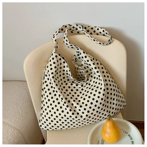 Detail of beige polka dot hobo bag with EMIS woven label hanging on a chair
