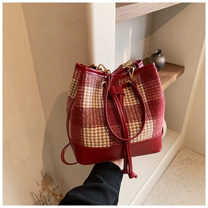 Détail du sac seau en tweed pied-de-poule rouge avec cordon en cuir et dorures