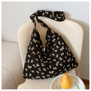 Detail view of black corduroy tote bag featuring white bow prints and brand label