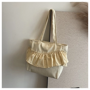 Detail of creamy off-white canvas tote bag featuring decorative pleated ruffles and straps
