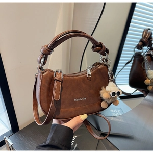 Details einer braunen Vintage-Satteltasche mit Knotengriff und Plüsch-Anhänger
