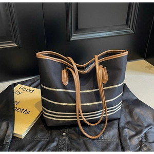 Close-up of black canvas tote bag with beige stripes on a leather jacket background