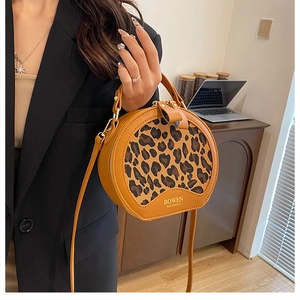 Detailed close-up of a leopard print round bag featuring top handle and logo detail