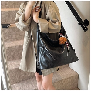 Dettaglio di una grande borsa hobo vintage nera con zip e un ciondolo a forma di cane di peluche