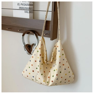 Close-up of beige canvas tote bag with colorful polka dots on a wooden rack