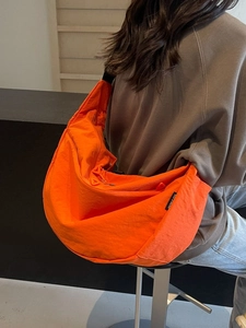 Minimalist vibrant orange nylon crescent crossbody bag with adjustable black strap
