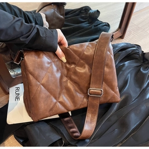Detail view of dark brown quilted crossbody bag with soft padded leather and adjustable strap