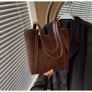 Detail of dark brown suede leather tote bag with long handles in a chic urban setting