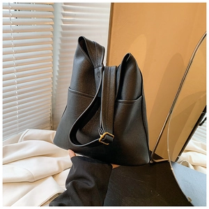 Detail of black pebbled leather tote bag featuring gold buckle and side pocket