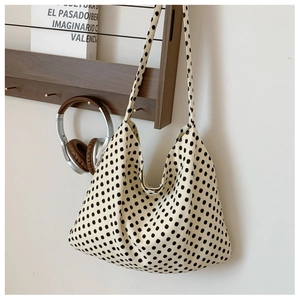 Artistic detail of canvas hobo bag with black polka dots on wooden hanger