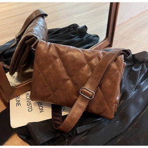Detail of vintage brown quilted crossbody bag with rhombic stitching and metal buckle