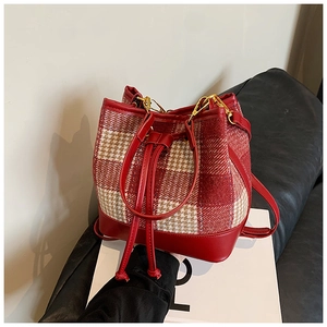 Détail du sac seau à carreaux rouges montrant le tissu en laine et le cordon en cuir