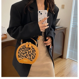 Detailed view of leopard print circular handbag with brand logo and detachable shoulder strap