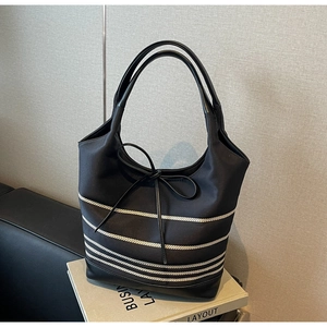Detail of black tote bag with silver stripes and leather handles on a business book