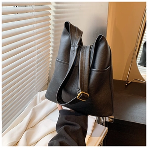 Close-up of black matte shoulder bag with a folding design and gold metal buckle